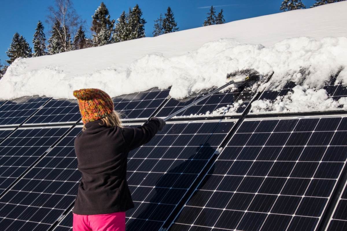 woman removes snow from solar panels